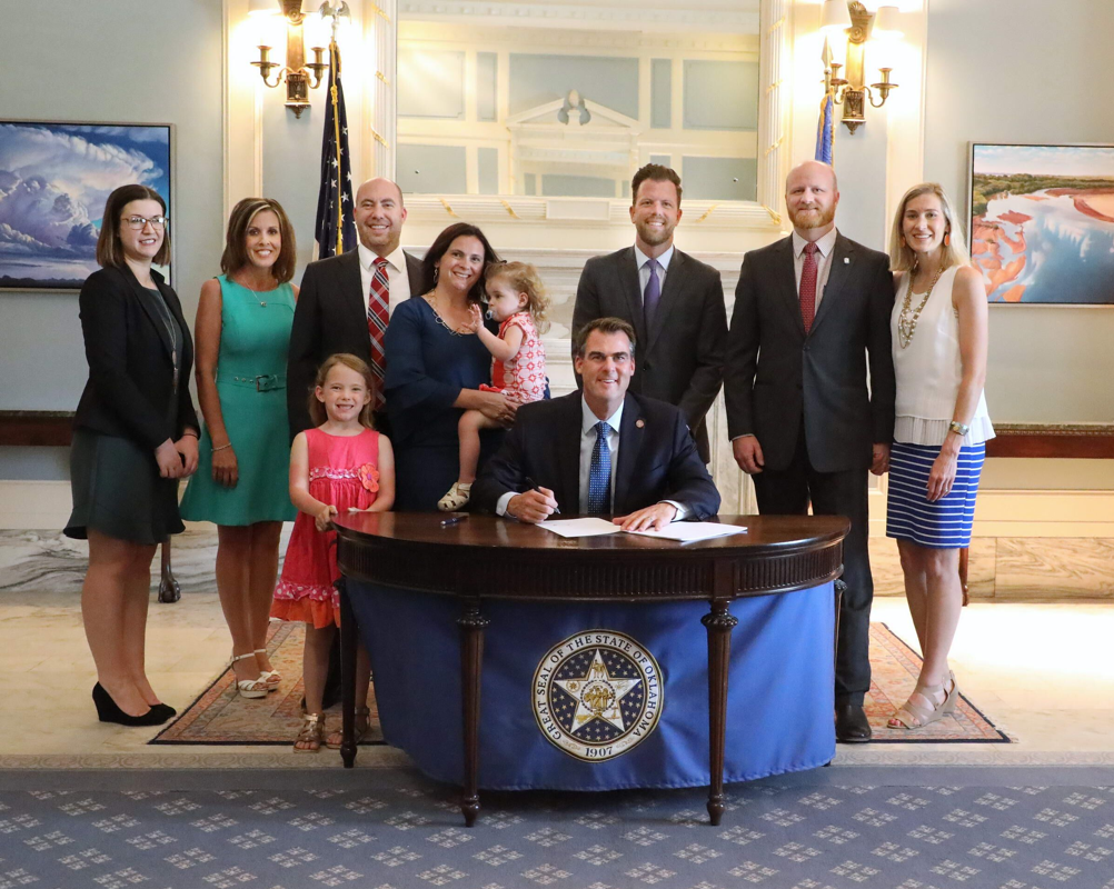 Legislative Assistant Meagan Hansen, Gayle Garrett with Surrogate Solutions, Andy Long, Laura Long, daughters Maddie and Della, Gov. Kevin Stitt, Rep. Jason Dunnington, D-Oklahoma City, Sen. Brent Howard and Jennifer Howard gathered in the Governor’s Blue Room for the recent ceremonial signing of legislation creating the Oklahoma Gestational Agreement Act. Howard and Dunnington were principal authors of the legislation.
