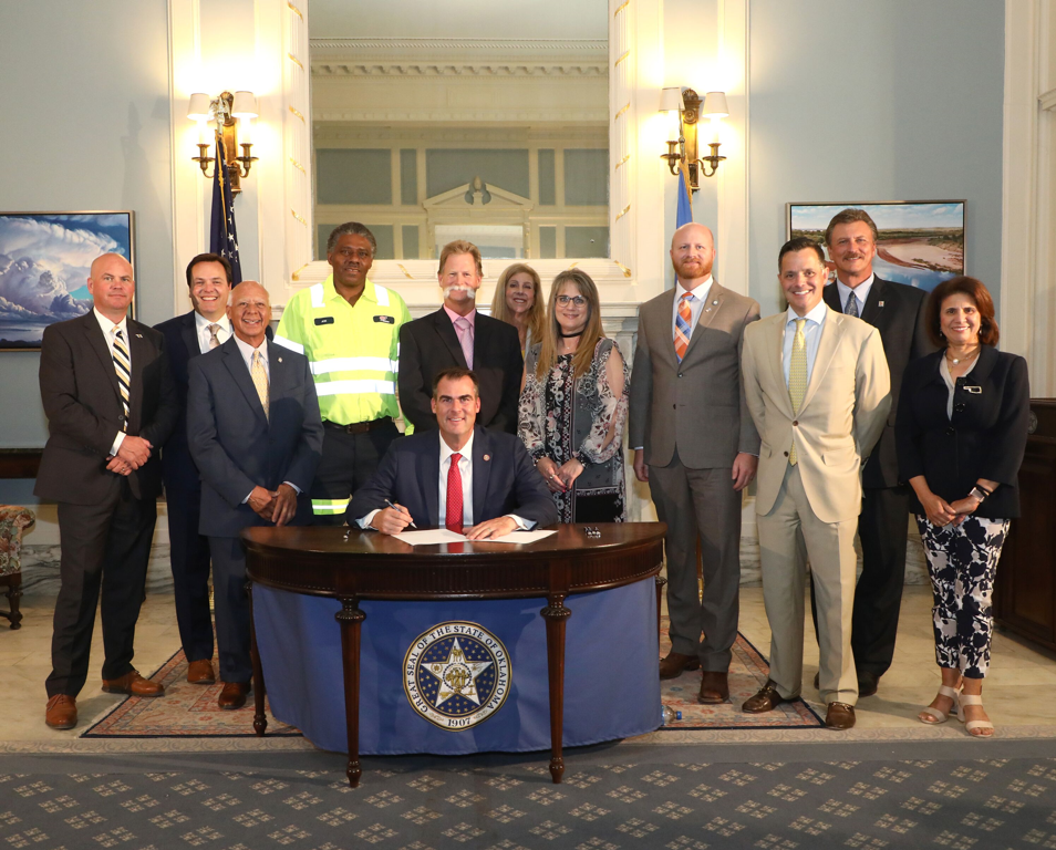 Representatives of law enforcement, state agencies, safety organizations and other officials gathered for a ceremonial signing of Senate Bill 89 by principal Senate author Sen. Brent Howard and principal House author, Rep. Charles Ortega. Pictured from left to right, Sheridan O/Neal with the Oklahoma Department of Public Safety (DPS), Taylor Henderson, the Oklahoma Department of Transportation (ODOT), Rep. Ortega, Joe Snell, AAA, Roger Straka, ODOT, Leslie Gamble, AAA, Stephanie Richardson, ODOT, Sen. Howard, Sec. of Public Safety, Chip Keating, Sec. of Transportation Tim Gatz, Terri Angier, ODOT and Gov. Kevin Stitt, seated.
