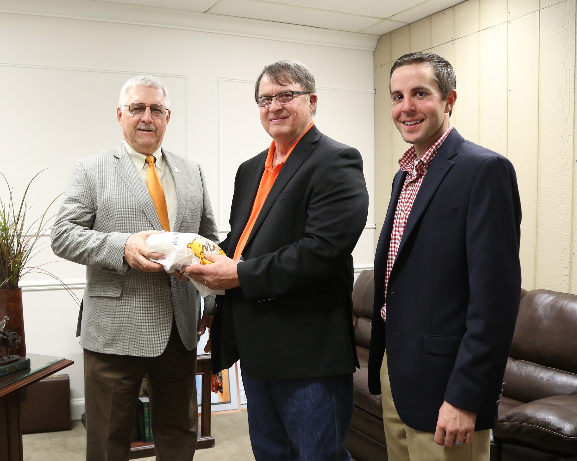 Senator Roland Peterson, R-Burlington, (left) welcomes delegates of the Oklahoma Wheat Growers Association, RJ Parrish of Hunter (center) and Travis Schnaithman of Garber in his office last week. Parrish and Schnaithman helped deliver Oklahoma-made bread to legislators for the annual Wheat Day at the Capitol.